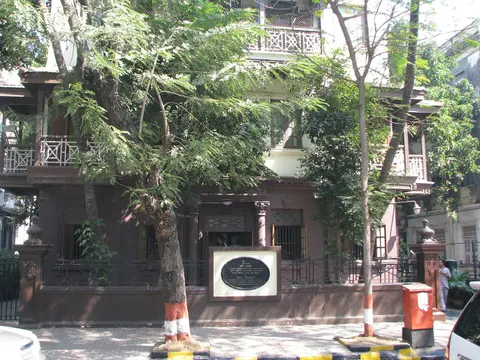 Mani Bhavan’s brown facade and plaque behind street trees on Laburnum Road