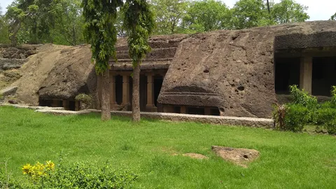 Pillared rock-cut caves at Mahakali, set into a low basalt hill above a green lawn