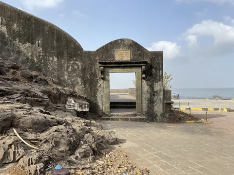 The restored gateway of Bandra Fort, a stone plaque above the arch and the sea beyond