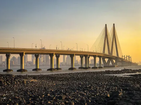 Bandra–Worli Sea Link at sunset, seen across a rocky low-tide shore
