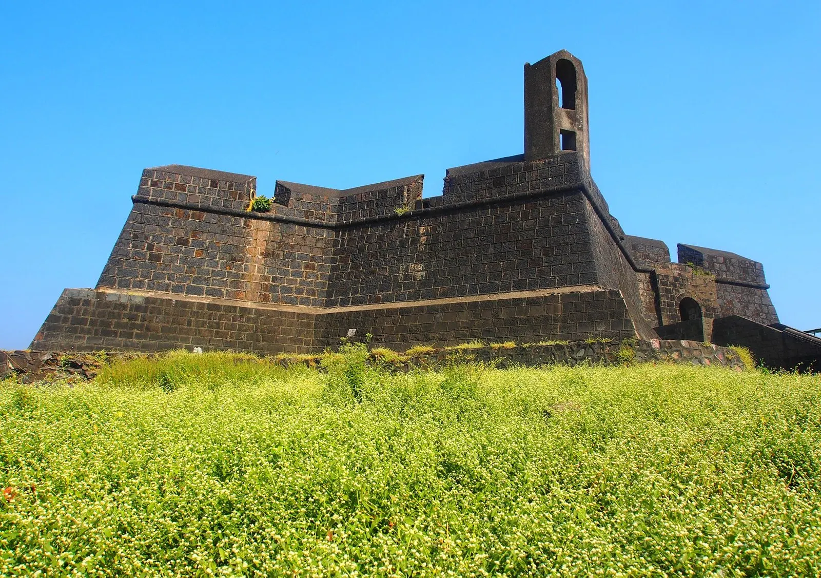 Stone walls and bastion of Worli Fort under a clear blue sky