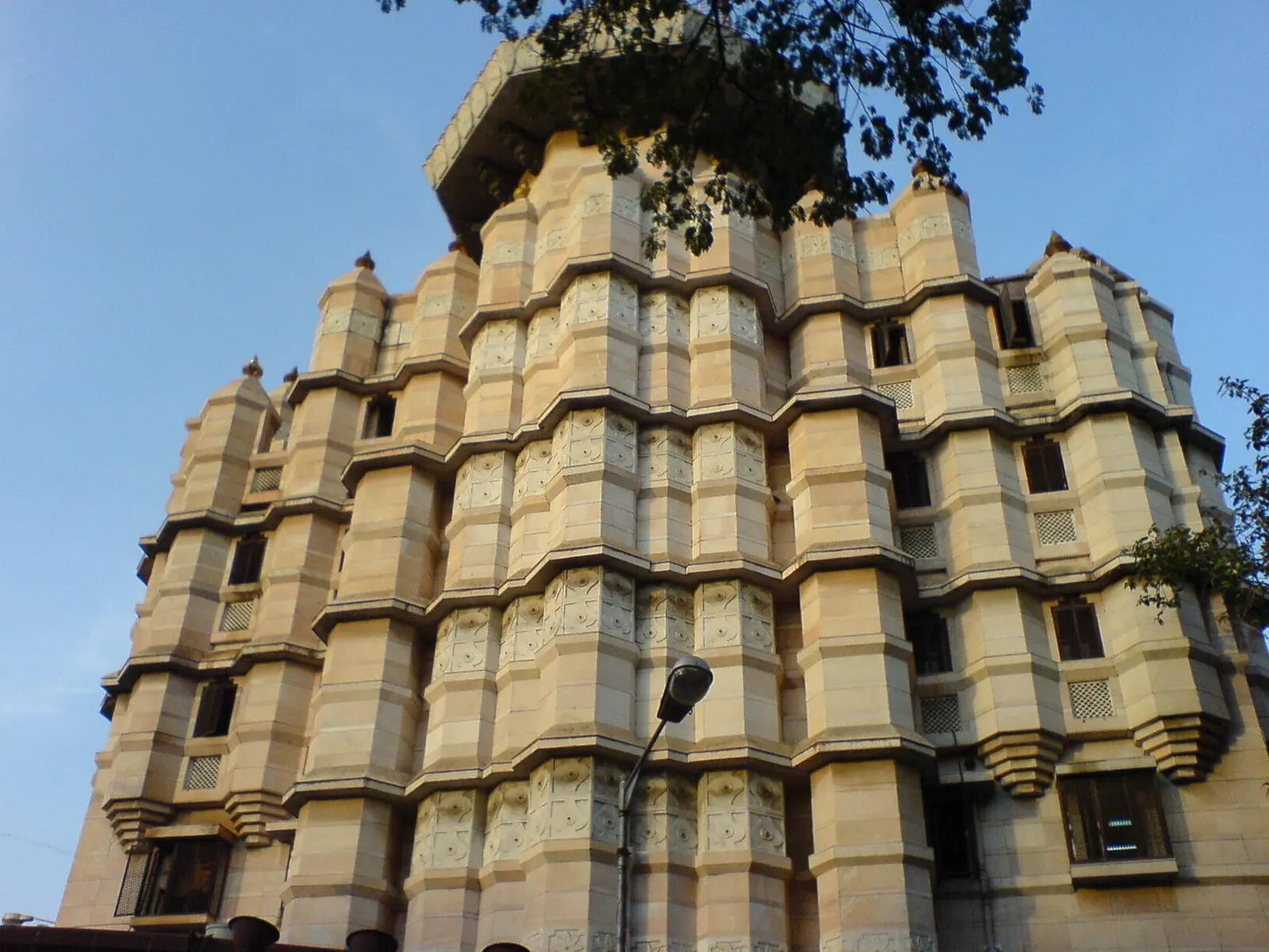 Tiered, carved cream stone walls of Siddhivinayak Temple seen from below