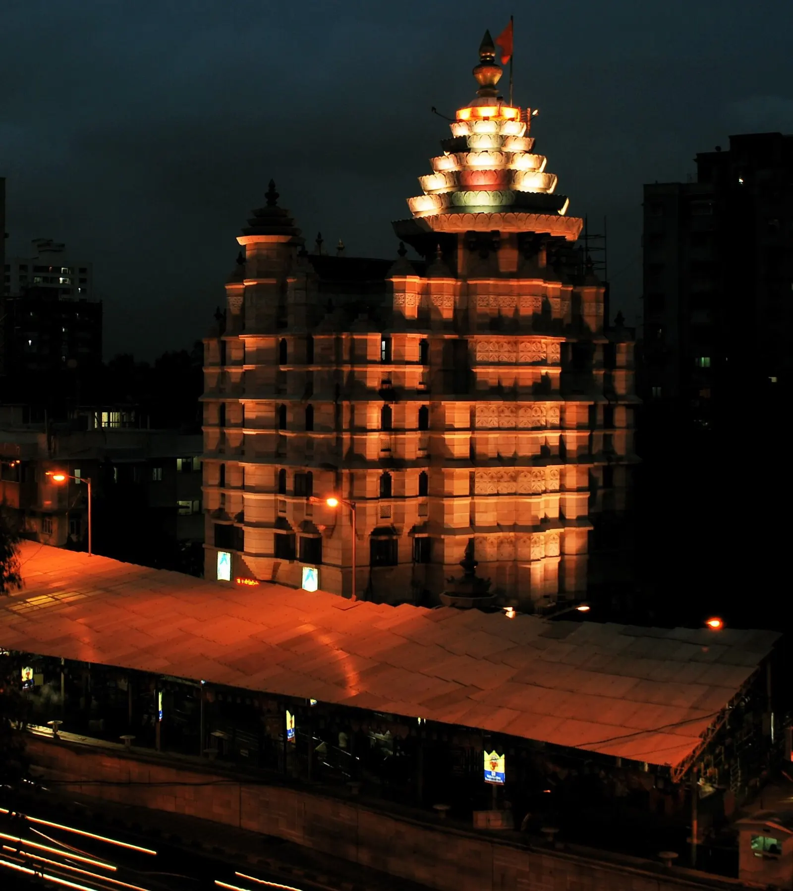 Siddhivinayak Temple lit in warm orange light at dusk above its covered queue canopy