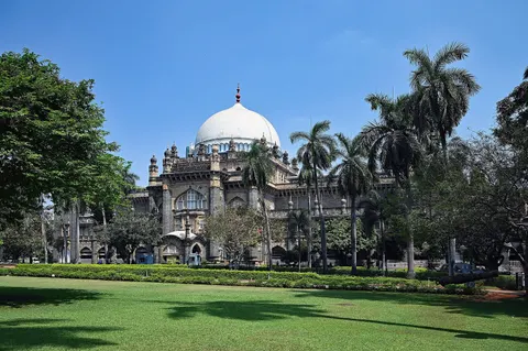 The white dome of CSMVS Museum rising above palms, seen across a wide green lawn