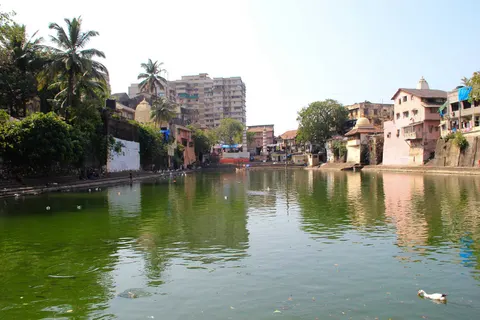 Green water of Banganga Tank reflecting palms, temples and old houses along its banks