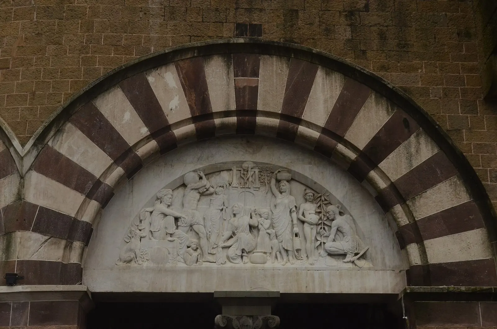 Carved stone relief above a striped arched doorway at Crawford Market